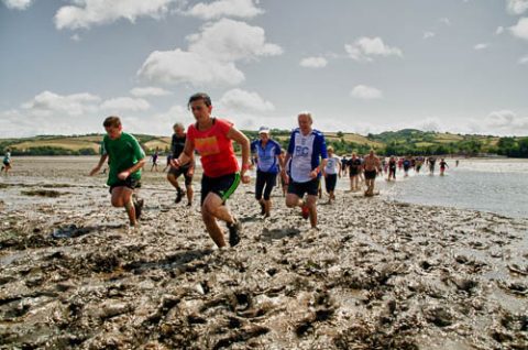 A photo of lots of runners taking part in The Mud Race across the River Teign at low tide