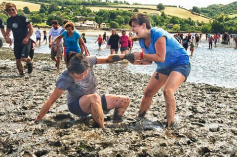 A photo of two ladies having fun running in The Mud Race across the River Teign at low tide